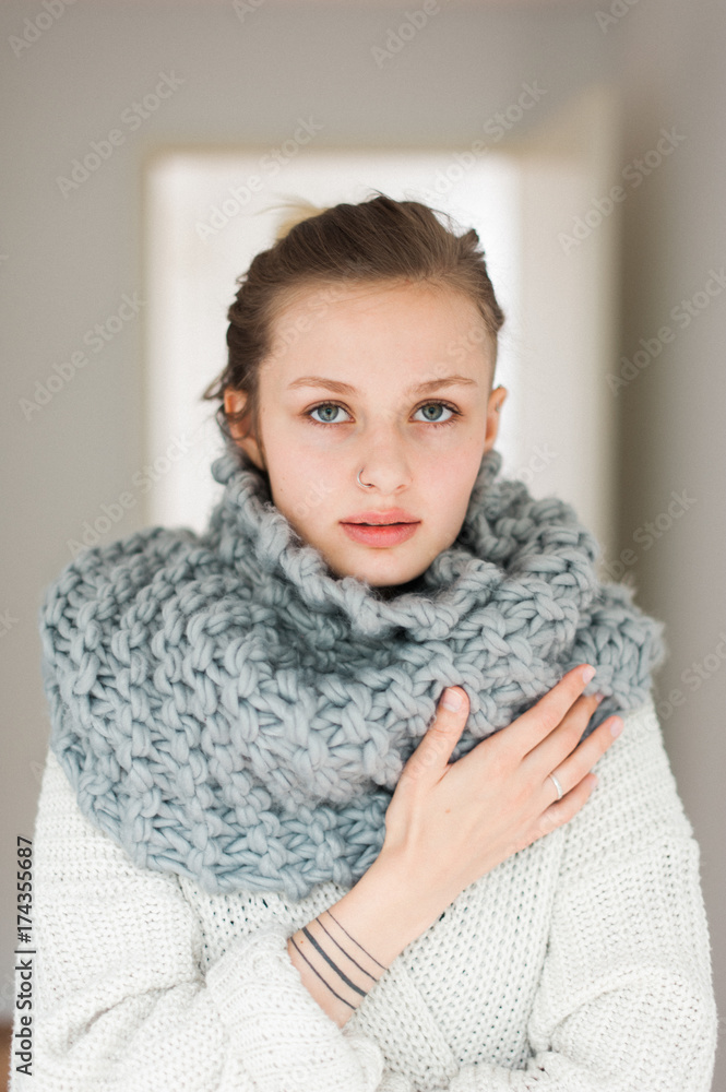 Young Fashionable Woman Wearing a Warm Scarf and Sweater Indoors Young Fashionable Woman Wearing a Warm Scarf and Sweater Indoors