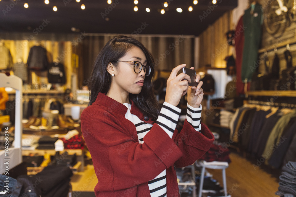 Stylish woman taking pictures with her phone in local downtown shop Stylish woman taking pictures with her phone in local downtown shop