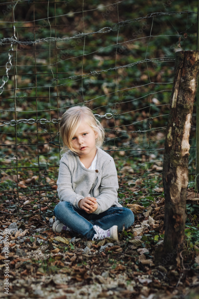 portrait of a sitting thoughtful looking cute little girl outdoors portrait of a sitting thoughtful looking cute little girl outdoors