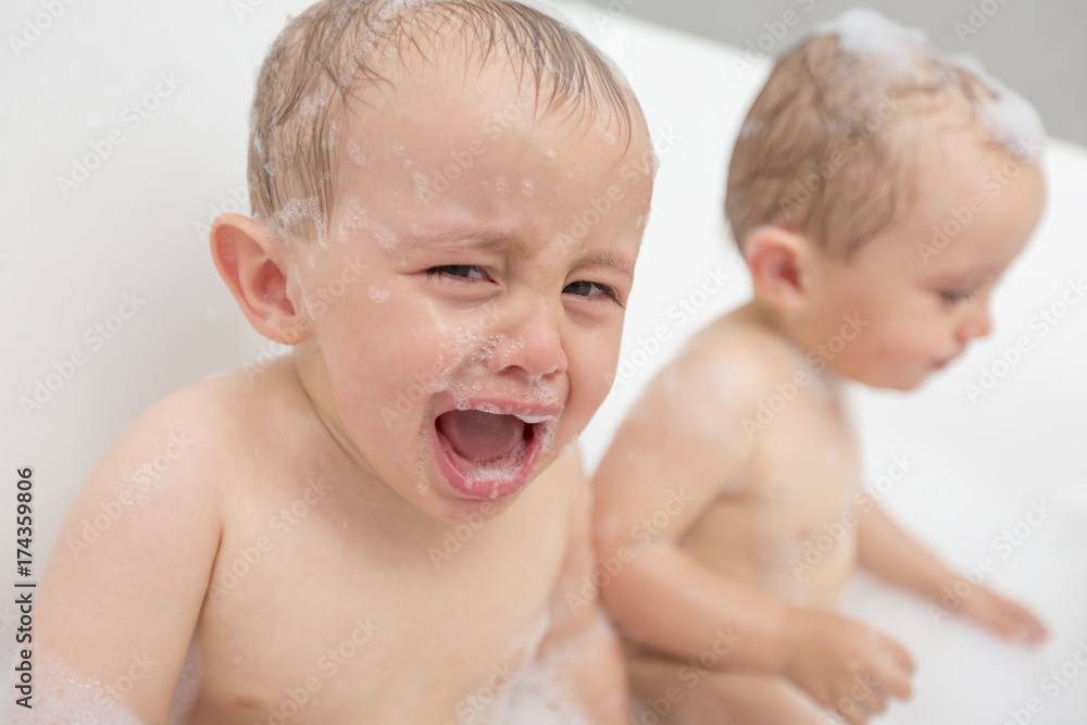 Fotka „Crying baby by in a bathtub. Infant kid sreaming while taking a bath.“ ze služby Stock