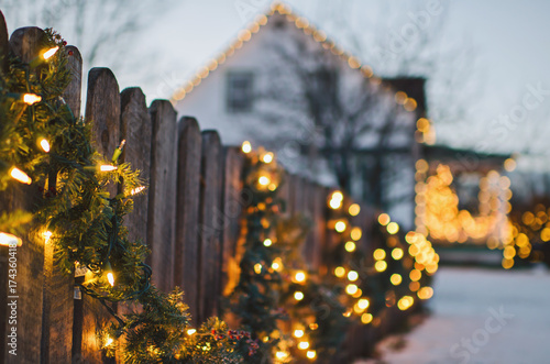 Holiday lights and garland adorn wooden fence photo