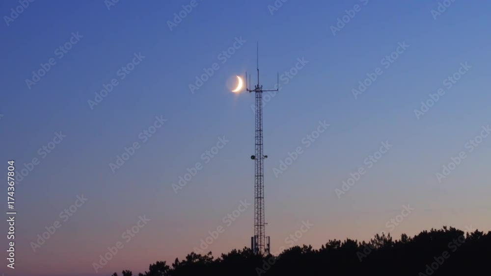 crescent moon sets behind hilltop cell phone mast ZOOM IN EASE crescent moon sets behind hilltop cell phone mast ZOOM IN EASE