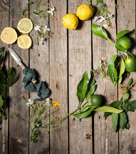 Lemons and limes on an old wood background with a vintage knife and some azahar flowers photo