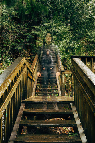 Long Exposure Of Man Standing On Steps Of Forest Trail Staircase