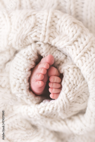 Close-up of newborn baby boy's feet wrapped in knitted blanket