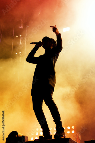Silhouette of an unrecognizable man singing rap photo