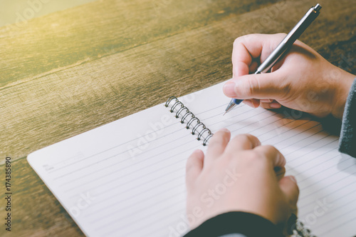 women hand with pen writing on notebook.