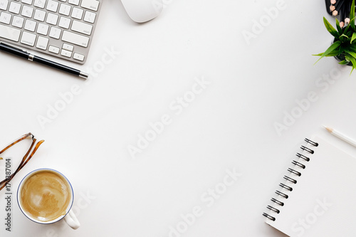 Stylish minimalistic workplace with keyboard, notebook, office plant, notebook, glasses in flat lay style. White background. Top view.
