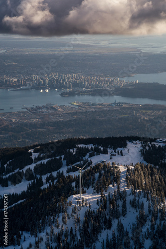 Aerial view of Grouse Mountain and Vancouver Downtown City  BC  Canada  in the background. Picture taken during a cloudy winter sunset.