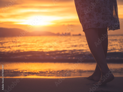 Silhouette of woman walking alone on the beach during sunset. Emotion, sad woman concept.