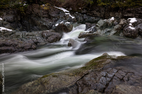 Nature view on the snow covered valley with the river flowing in between the rocks. Picture taken near Tofino  Vancouver Island  British Columbia  Canada.