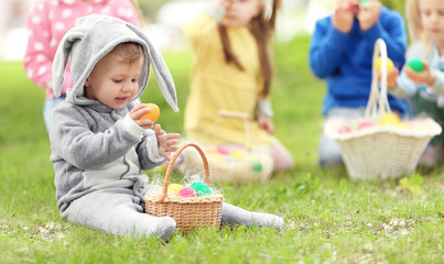 Cute little boy with basket on green grass in park. Easter egg hunt concept