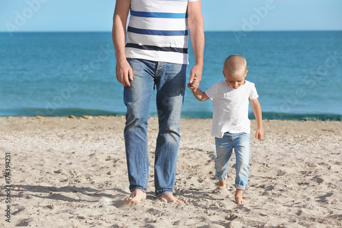 Cute boy with grandfather on sea beach