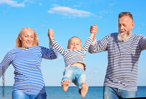 Cute boy with grandparents on sea beach