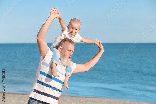 Elderly man playing with grandson on sea beach