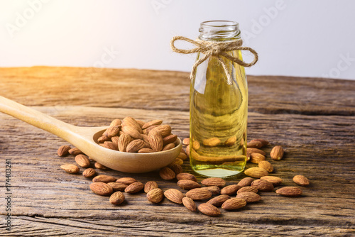 Peeled almonds with bowl and Bottle of almond oil on rustic wooden