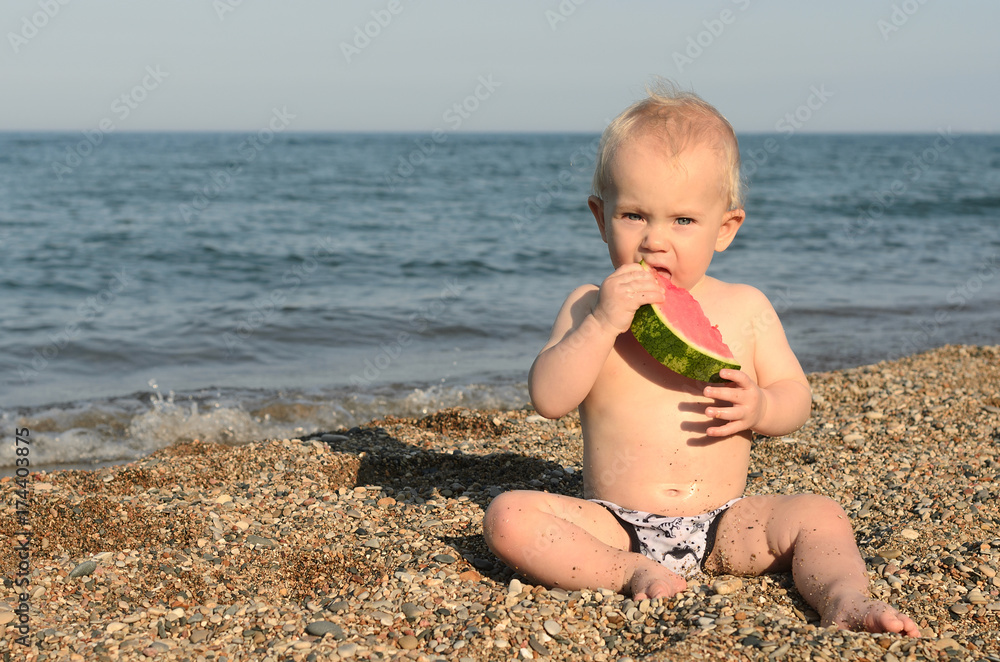 cute baby boy eating fresh watermelon at the beach cute baby boy eating fresh watermelon at the beach
