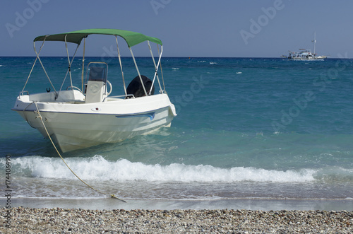 Moored boat on the beach of Kolymbia and the walking yacht in the Mediterranean Sea (Rhodes, Greece).