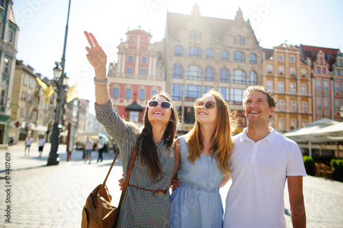 Three young people stand on the square of the ancient city.