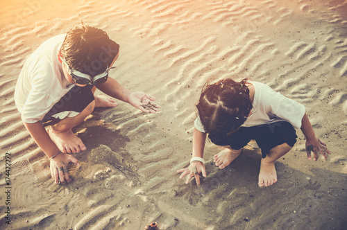 Asian children digging in the sand. Concept of connecting children with nature.