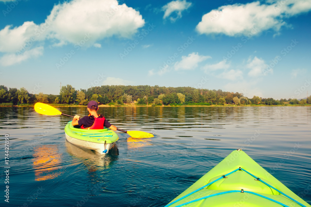 Fototapeta premium Boy in life jacket on green kayak