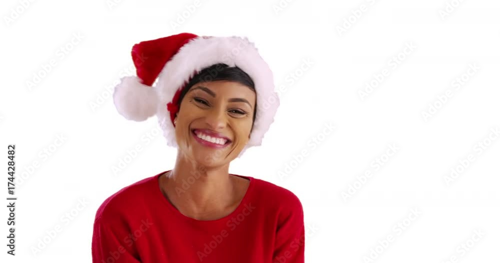 Close up of cheerful woman in red sweater laughing at camera on white background. Portrait of cute black female playing with festive Santa hat in studio with copyspace Close up of cheerful woman in red sweater laughing at camera on white background. Portrait of cute black female playing with festive Santa hat in studio with copyspace