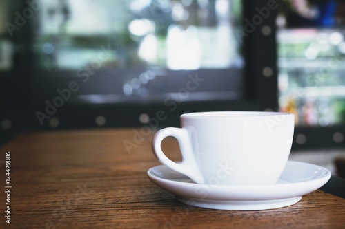 The coffee cup is placed on the table wooden in the coffee shop style loft modern.