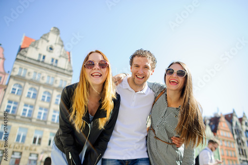 Three young people stand on the square of the ancient city.
