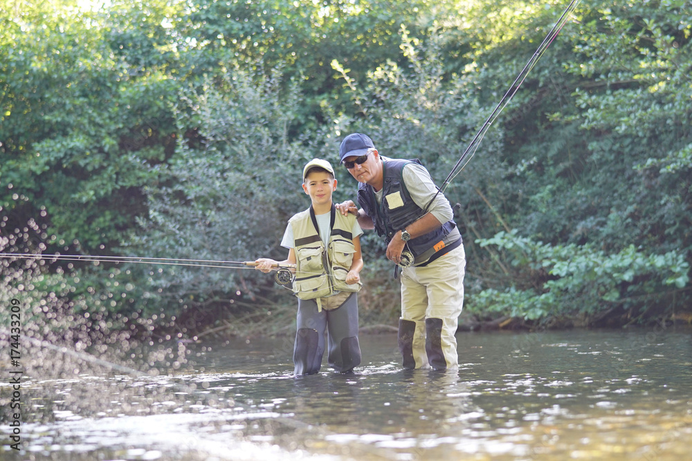 Father teaching son how to fly-fish in river Father teaching son how to fly-fish in river