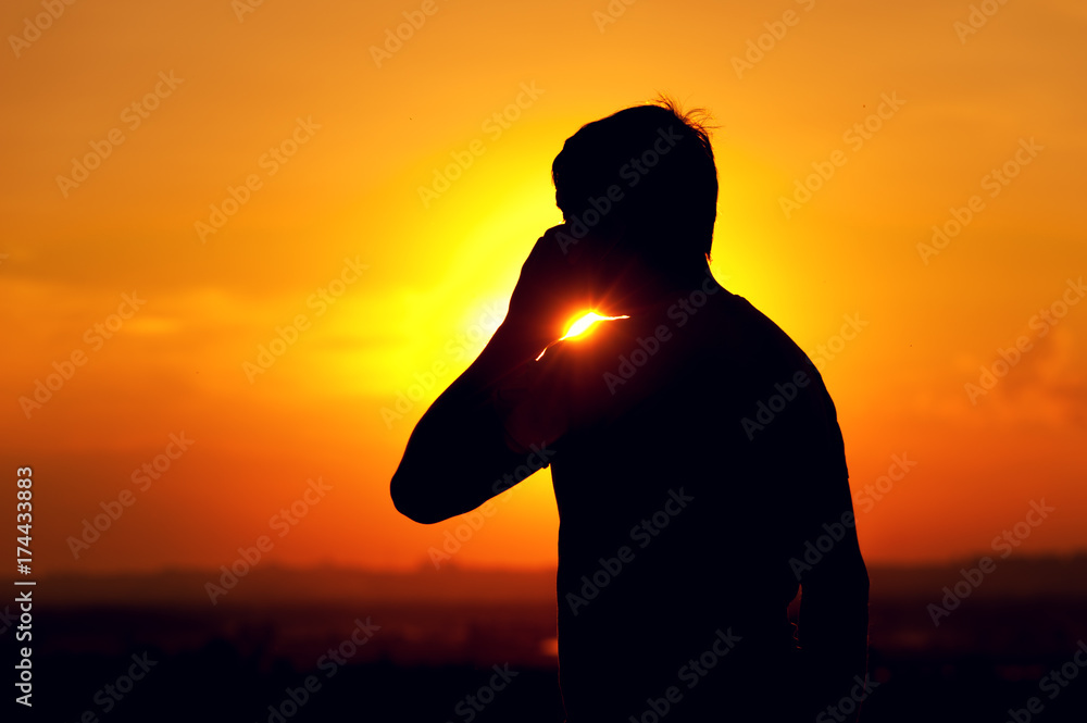 Silhouette of young man talking on the phone