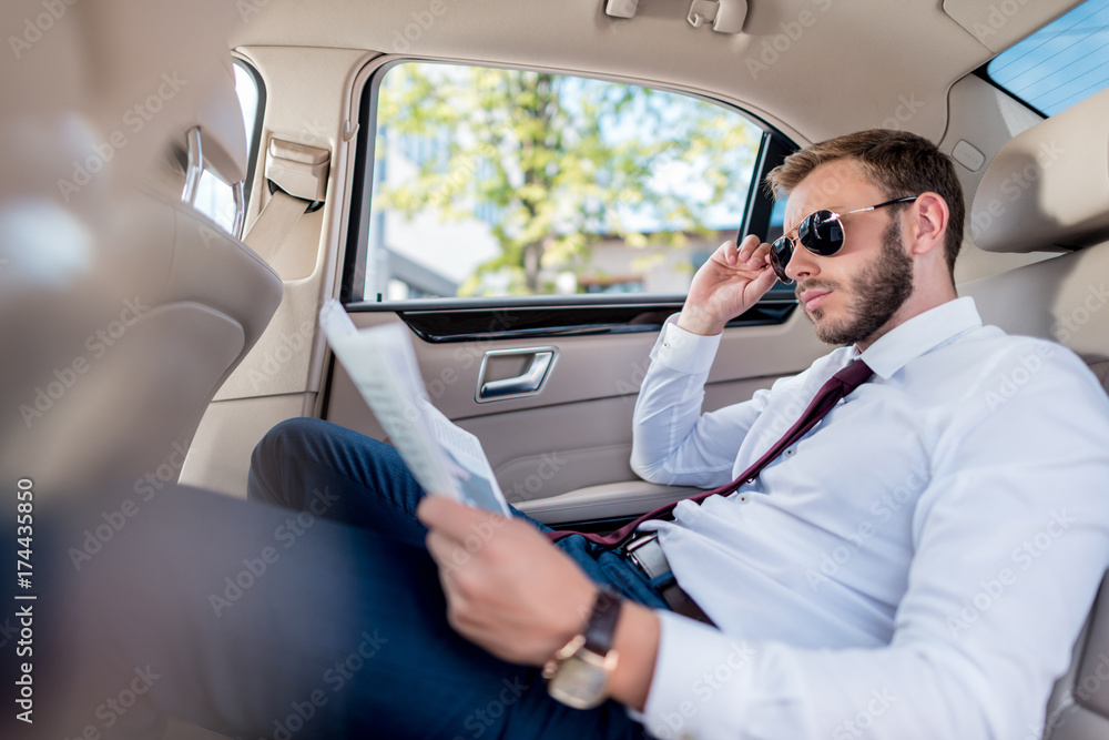 businessman with newspaper in car businessman with newspaper in car