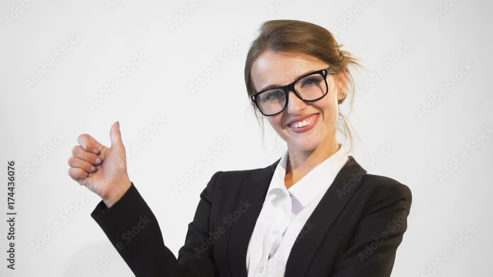 Happy young dark hair caucasian businesswoman, in a white blouse and a black jacket, is showing her thumb up in the white background, isolated, slow motion Happy young dark hair caucasian businesswoman, in a white blouse and a black jacket, is showing her thumb up in the white background, isolated, slow motion