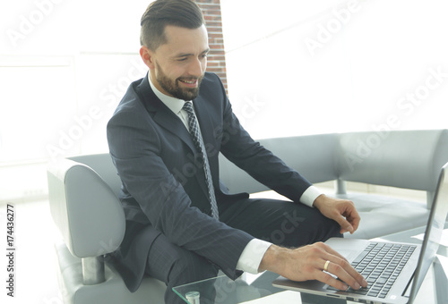 Smiling businessman browsing information on laptop,