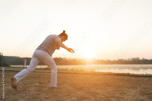 Athletic capoeira performer making movements on the beach