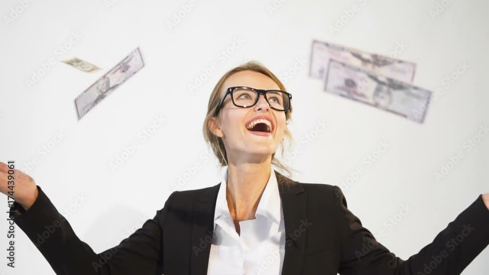 Contented young dark hair caucasian businesswoman, in a white blouse and a black jacket, is wondering of falling banknotes in the air joyfully in the white background, isolated, slow motion Contented young dark hair caucasian businesswoman, in a white blouse and a black jacket, is wondering of falling banknotes in the air joyfully in the white background, isolated, slow motion