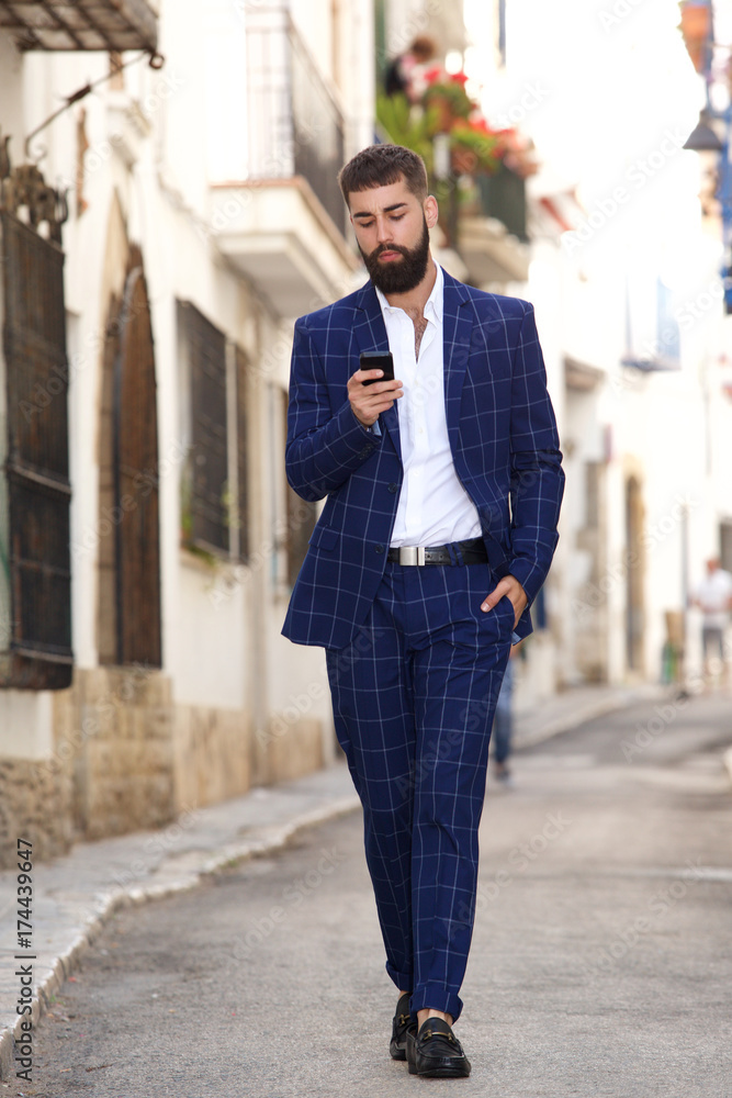 Full length businessman walking in city street with cell phone Full length businessman walking in city street with cell phone