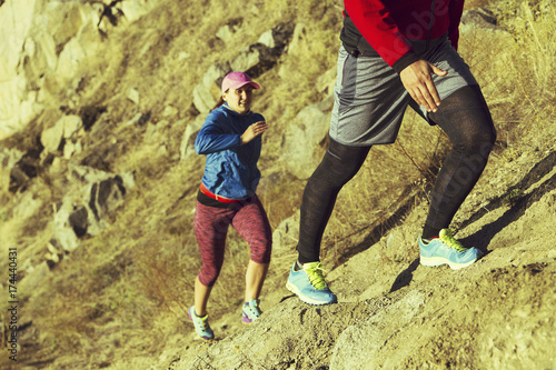 Trail running couple runners racing on mountain path in volcanic rocks nature landscape in summer outdoor. Ultra running race run.