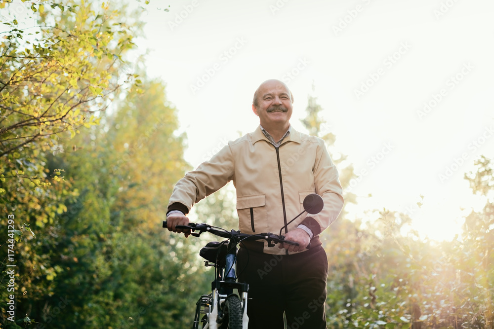 Senior man go for a walk with bike in countryside