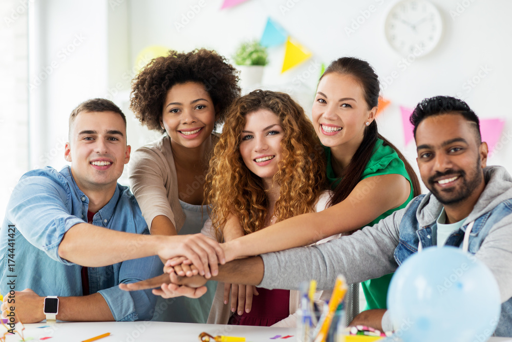 happy team at office party holding hands together happy team at office party holding hands together