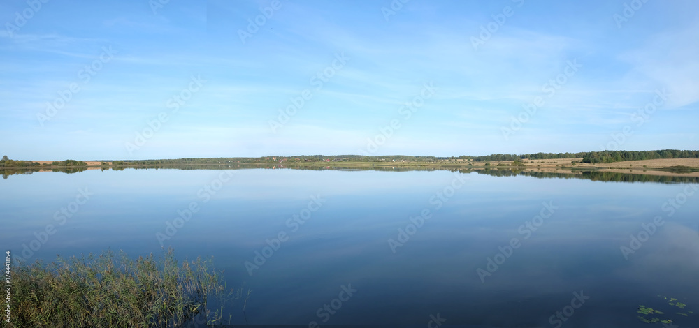 Panoramic view of countryside landscape with hills, lake, hills and forest far away in sunny summer day