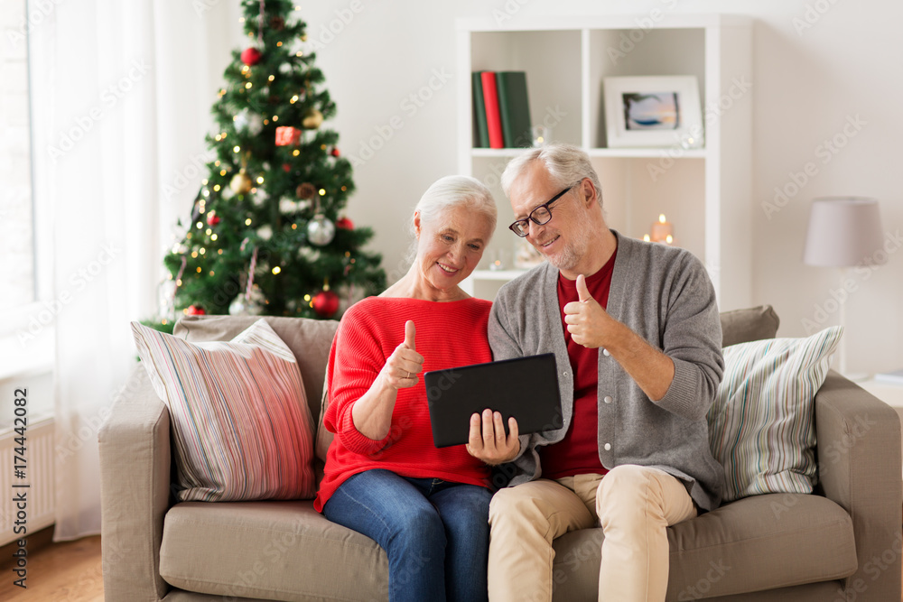 Obraz premium happy senior couple with tablet pc at christmas