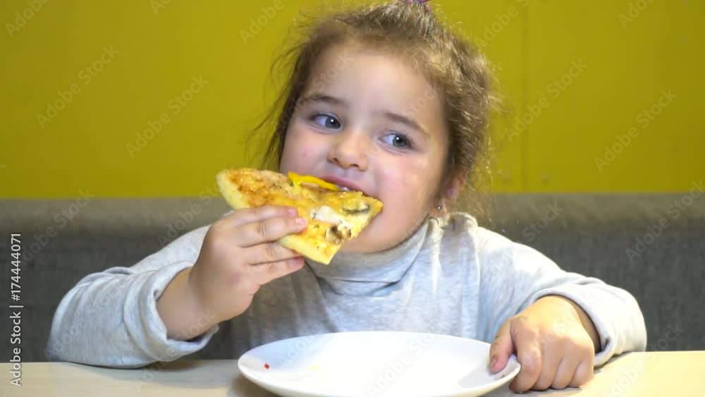 Little child girl portrait funny eat slice of pizza at cafe Little child girl portrait funny eat slice of pizza at cafe
