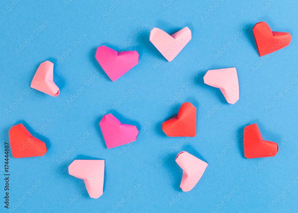 Red, Bright and Pale Pink Paper Origami Hearts on Blue Background