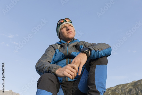 Obraz na płótnie A mischievous smiling hiker sits on a stone and enjoys the sunrise