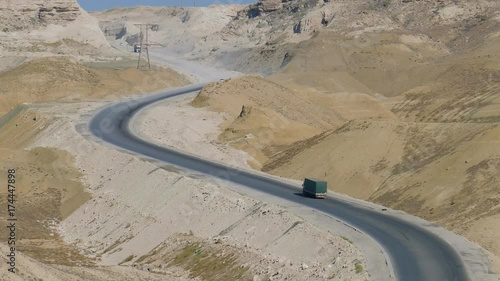 One truck slowly climbs into the groove on a sunny road in the middle of the hills