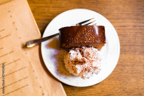 The close-up composition of the chocolate cake decorated with fresh cream placed on the craft menu. photo