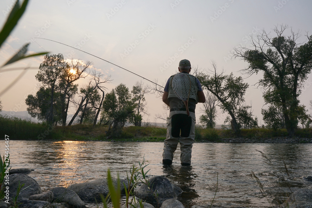 Fly fisherman fishing in river of Montana state, sunset Fly fisherman fishing in river of Montana state, sunset
