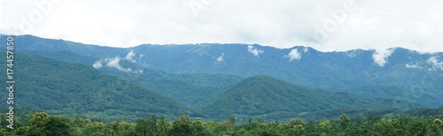 Panorama of green mountain range with soft white clouds