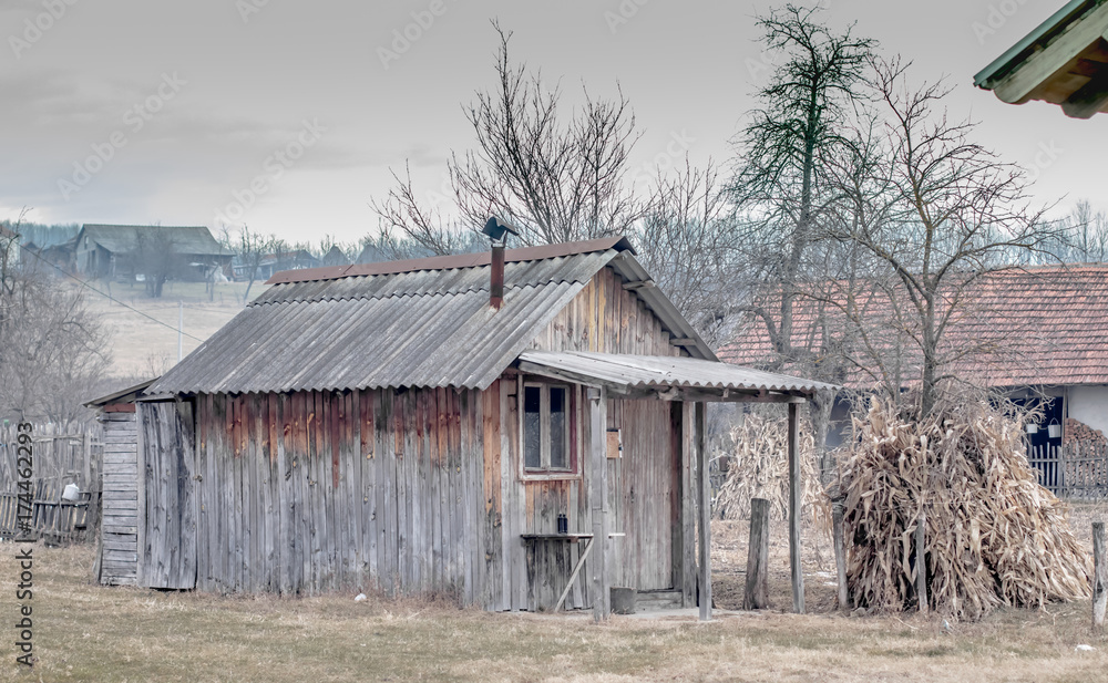 Rustic wooden shed with window at the background of haystack in serbian village. Rural landscape in the Balkans in winter or spring or autumn. Calmness loneliness silence. Poverty misery concept. Rustic wooden shed with window at the background of haystack in serbian village. Rural landscape in the Balkans in winter or spring or autumn. Calmness loneliness silence. Poverty misery concept.
