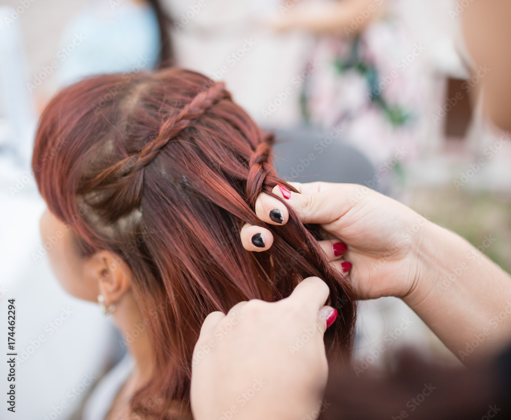 Naklejka premium the stylist weaves the female braids on the head